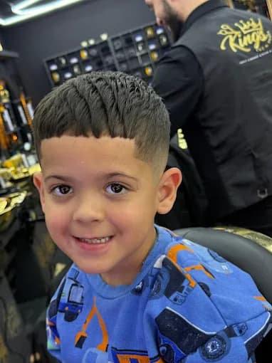 Smiling boy with a fresh textured crop and skin fade haircut at the barbershop.
