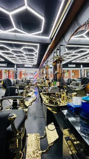 Luxurious barbershop with ornate gold and black chairs, gold sinks, and hexagonal ceiling lights.
