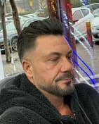 Man with a dark pompadour hairstyle and groomed beard wearing a black sherpa hoodie.